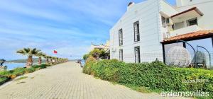 a white building next to the ocean next to a street at Denize sıfır benzersiz villa in Kusadası +14 photos