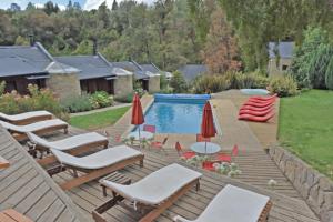 - une terrasse avec des chaises longues et des parasols à côté de la piscine dans l'établissement Rosas Blancas Apart Hotel By Visionnaire, à San Martín de los Andes