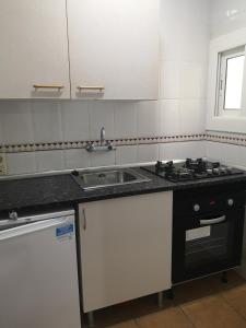 a kitchen with a sink and a stove at Apartamentos Famara in Lloret de Mar