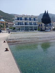 um grande edifício em frente a uma massa de água em Hotel Blue Sea em Tyros
