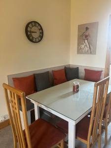 a table and chairs with a couch and a clock at Racecourse Lodge Apartment in Clifden