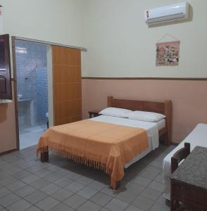 ein Schlafzimmer mit einem Bett und ein Badezimmer mit einem TV in der Unterkunft Pousada Dos Cajueiros in Paripueira