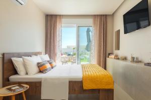 Un dormitorio con una cama grande con ventana. en Lago Beach Living, en Faliraki