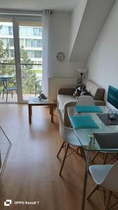 ein Wohnzimmer mit einem Sofa, Stühlen und einem Tisch in der Unterkunft Apartament za wydmą Sosnowa 13 in Mielno
