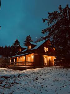 a large wooden house in the snow at night at Brvnara La Forêt in Žabljak