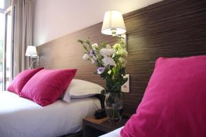 a bedroom with a vase of flowers on a bed at Hotel Menton Riviera in Menton