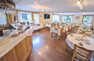 un restaurante con mesas, mesas blancas y sillas en Hosteria Monteverde by Visionnaire en San Martín de los Andes