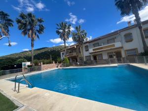 a swimming pool in front of a building with palm trees at Casa Rural las Rosas de Benaojan in Benaoján +78 photos