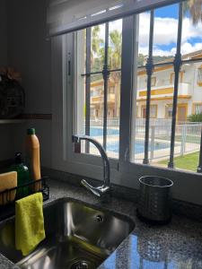 um lavatório de cozinha e uma janela com vista para uma piscina em Casa Rural las Rosas de Benaojan em Benaoján