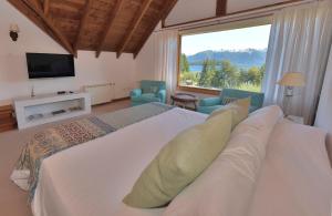 een slaapkamer met een groot bed en een groot raam bij Hosteria Puertas Del Sol by Visionnaire in Villa La Angostura