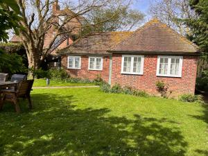 a brick house with a table and chairs in a yard at Green Cottage in grounds of Grade II* Frognal Farmhouse in Sittingbourne