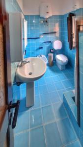 a blue tiled bathroom with a sink and a toilet at Oasi CalaCapra - Palau Costa Smeralda in Proiettore