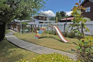 a playground with a slide in a yard at Cabañas Humo Azul by Visionnaire in San Martín de los Andes