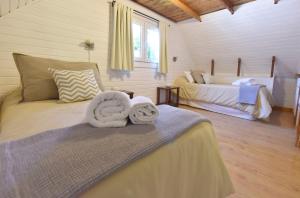 1 dormitorio con 2 camas y toallas. en Cabañas Nonthue by Visionnaire en San Martín de los Andes