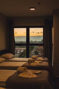 2 letti in una camera d'albergo con finestra di Britto Hotel a Aparecida