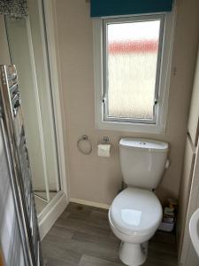 a bathroom with a toilet and a window at Lyons Robin Hood, RHYL "The Beach Hut" in Rhyl