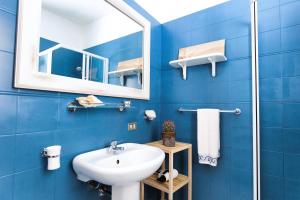 een blauwe badkamer met een wastafel en een spiegel bij Casa Angela Lipari in Canneto +26 foto's