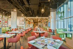 a restaurant with tables and chairs and windows at IntercityHotel Bawshar Muscat in Muscat
