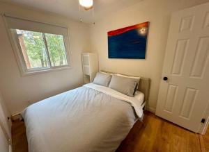 1 dormitorio con 1 cama blanca y ventana en Repère d'Eastman (accès au lac/foyer/randonnée), en Eastman
