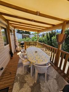 una mesa y sillas en una terraza de madera en Casa Luisa Mobil Home, en Canet-en-Roussillon