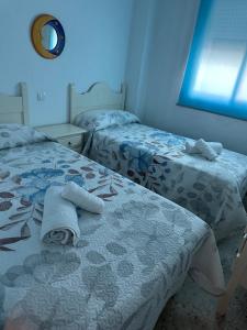 um quarto com 2 camas e toalhas em Nuevo Portil em El Portil