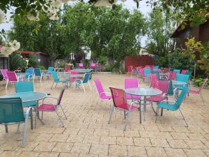 a group of tables and chairs with colorful chairs at La Motanu in Ghermăneşti