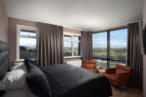 um quarto com uma cama, uma cadeira e janelas em Hotel Varmaland em Varmaland