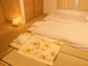 a bedroom with two beds and a rug on the floor at かんたろうもねたろうの母家 in Furano