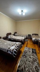 three beds in a room with wooden floors at Guest House Janel in Cholpon-Ata