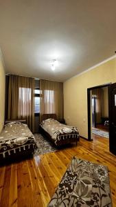 two beds in a large room with wooden floors at Guest House Janel in Cholpon-Ata