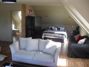 a living room with a white couch and a bed at Cityescape in Kaimai