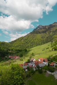 un groupe de maisons dans un champ verdoyant avec une montagne dans l'établissement Hiša Juliana - Your Escape From Massive Tourism, à Podbrdo
