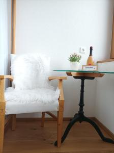 uma mesa de vidro com uma cadeira branca ao lado de uma mesa de vidro com uma mesa de vidro em Faschina Apartment - Top 1 em Fontanella
