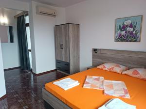 a bedroom with an orange bed and a cabinet at Coral Family Hotel in Chernomorets