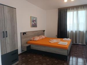 a bedroom with a bed with orange sheets and pillows at Coral Family Hotel in Chernomorets