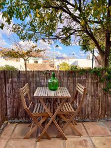 einem Holztisch mit zwei Stühlen und einer grünen Vase darauf in der Unterkunft Hostal del vino LA COSTERA in Altea