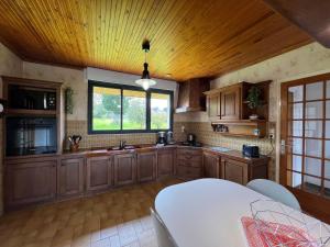 duża kuchnia z drewnianymi szafkami i drewnianym sufitem w obiekcie GRANIT COCOON w mieście Saint-Quay-Perros