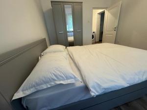 a bed with white sheets and pillows in a bedroom at Peony Apartament in Craiova