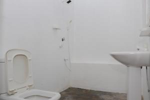 a white bathroom with a toilet and a sink at Emerald Bay in Arugam Bay
