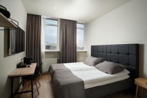 una camera con letto e scrivania e due finestre di Hotel Varmaland a Varmaland