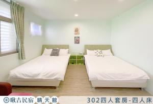 Duas camas num quarto com paredes brancas em 啾吉民宿晴天館 em Wujie
