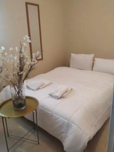 białe łóżko z wazą kwiatów na stole w obiekcie Maria’s apartment w mieście Amfilochia