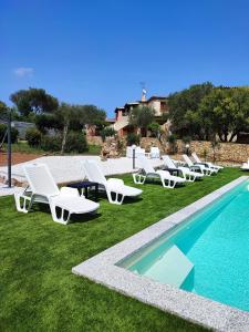 a group of white lounge chairs and a swimming pool at Antica Isola in Olbia