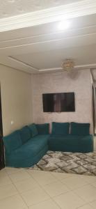 Superbe appartement F3 tout confort في أغادير: غرفة معيشة مع أريكة خضراء وتلفزيون بشاشة مسطحة