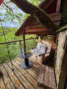 eine Holzterrasse mit einer Bank und einem Tisch in der Unterkunft Cabane Dans Les Arbres - Les Lutins in Mechmont