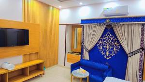 sala de estar con sofá azul y TV en Clifton Lodge Boutique Hotel en Karachi