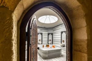 einen Torbogen, der in ein Badezimmer mit Badewanne führt. in der Unterkunft Utopia Cave Cappadocia in Ürgüp