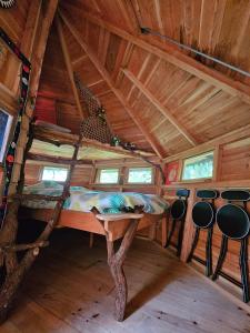 Bett in einem Holzzimmer mit Fenstern in der Unterkunft Cabane Dans Les Arbres - Les Lutins in Mechmont