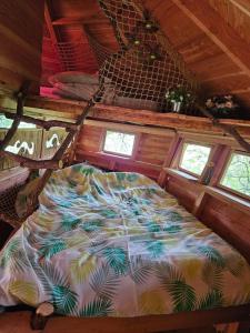 Bett auf der Rückseite eines Zimmers mit Fenstern in der Unterkunft Cabane Dans Les Arbres - Les Lutins in Mechmont