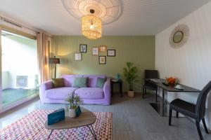 een woonkamer met een paarse bank en een tafel bij Sweet Inn - Maison Blanche in Juan-les-Pins